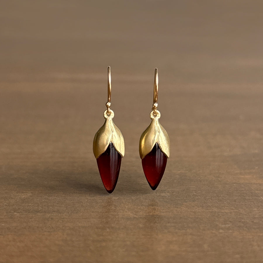 Gold earrings with red gemstones on a brown background