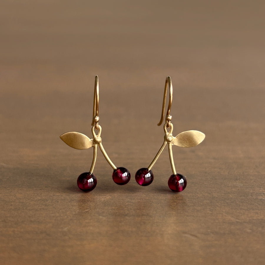 Gold earrings with red gemstones on a brown background