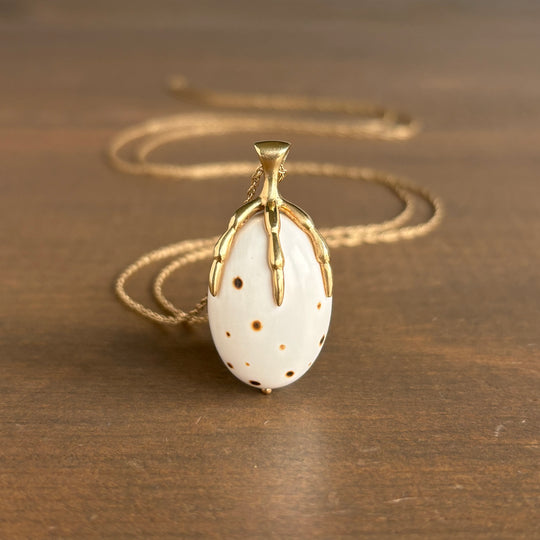 Gold necklace with a white pendant on a wooden surface