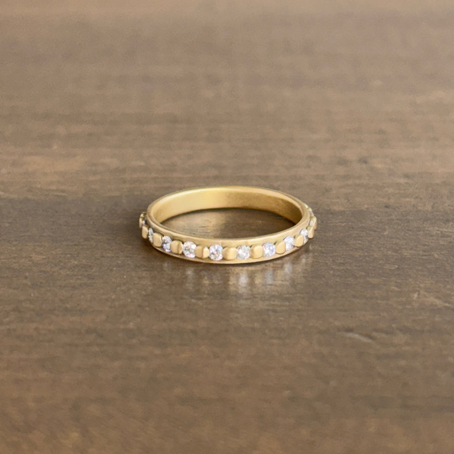 Gold ring with embedded diamonds on a wooden surface