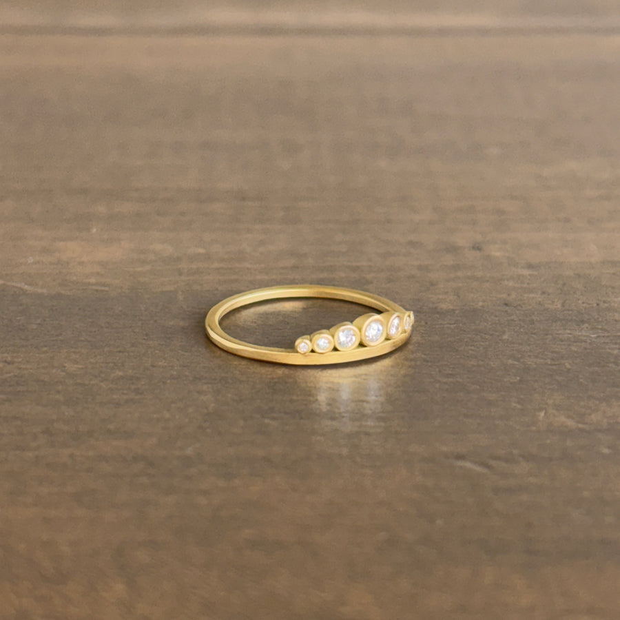 Gold ring with small diamonds on a brown surface