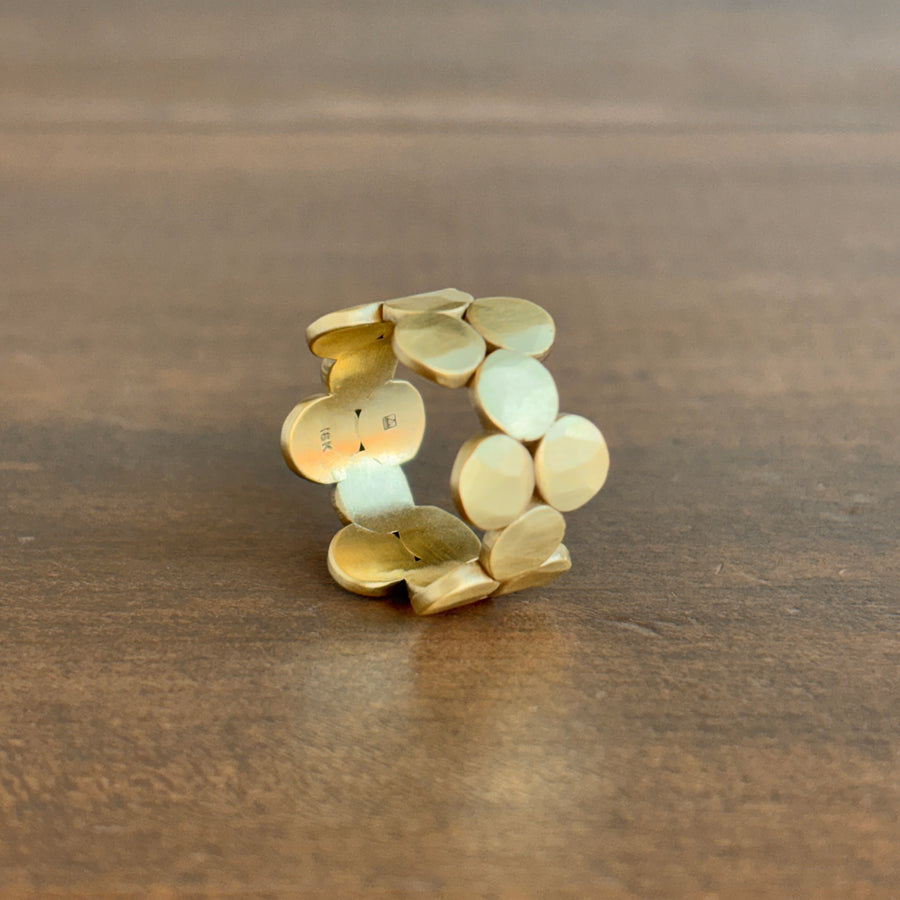 Gold ring with circular design on a wooden surface