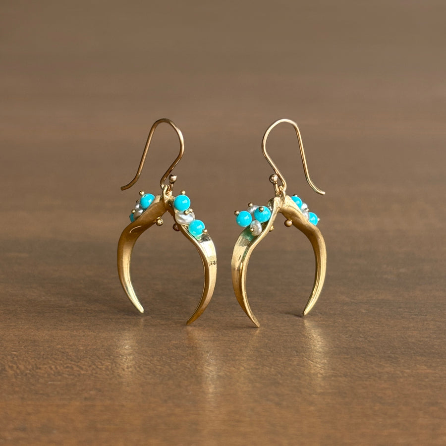 Gold earrings with turquoise stones on a brown background