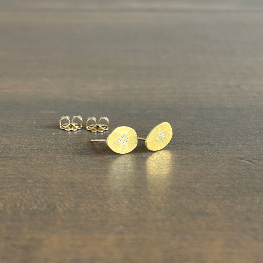 Gold earrings on a dark surface