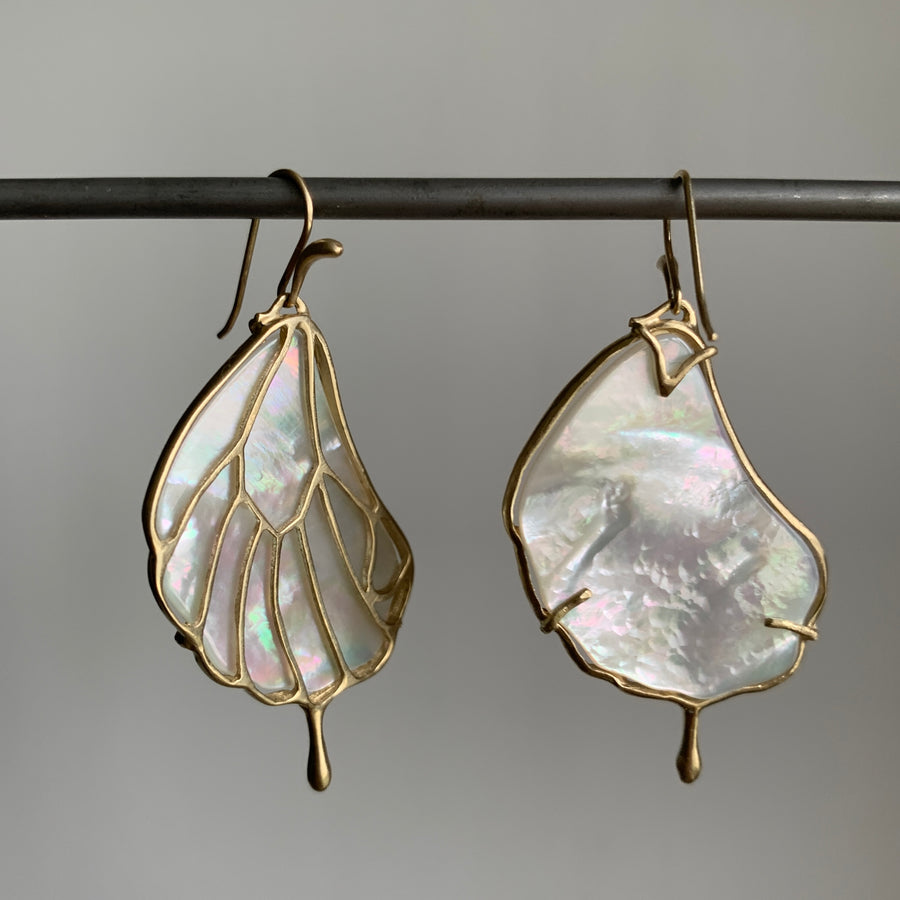 Pair of leaf-shaped earrings with gold detailing on a gray background