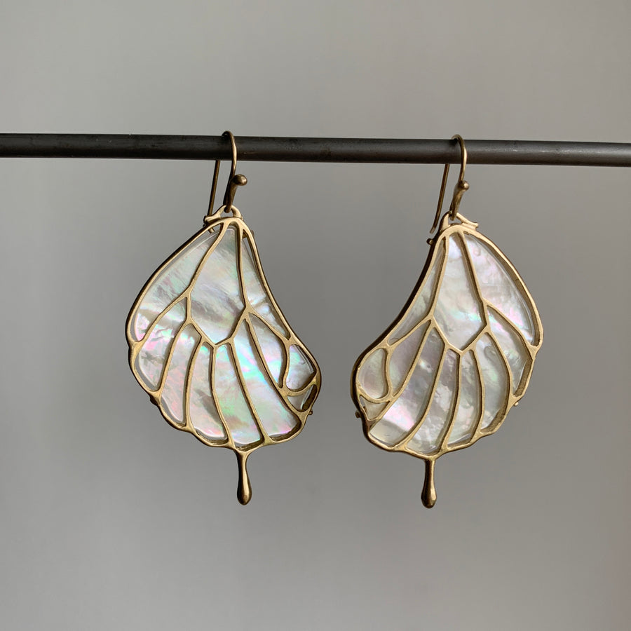 Pair of leaf-shaped earrings with a gold frame on a gray background