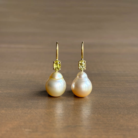 A pair of 18k yellow gold baroque South Sea pearl earrings with chrysoberyl accents, displayed against a plain background.