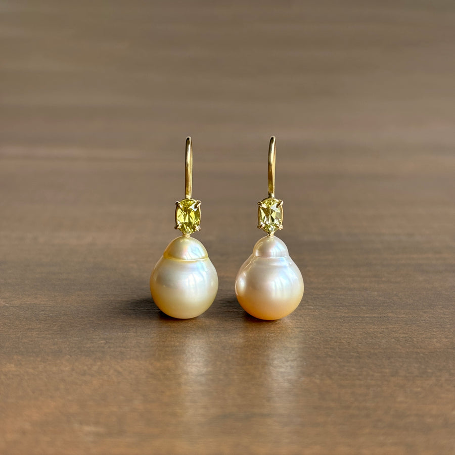 A pair of 18k yellow gold baroque South Sea pearl earrings with chrysoberyl accents, displayed against a plain background.