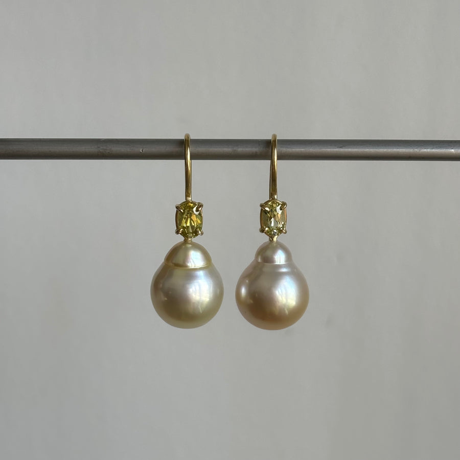 A pair of 18k yellow gold baroque South Sea pearl earrings with chrysoberyl accents, displayed against a plain background.