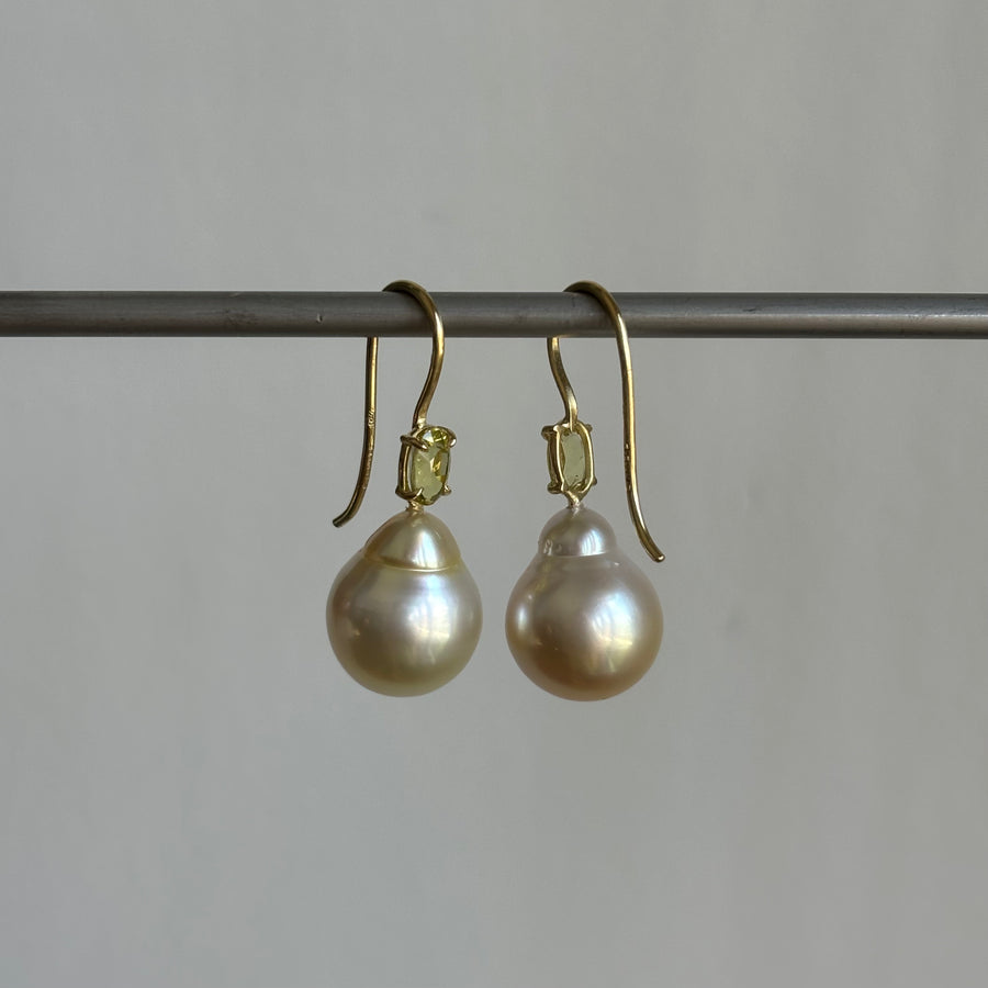 A pair of 18k yellow gold baroque South Sea pearl earrings with chrysoberyl accents, displayed against a plain background.