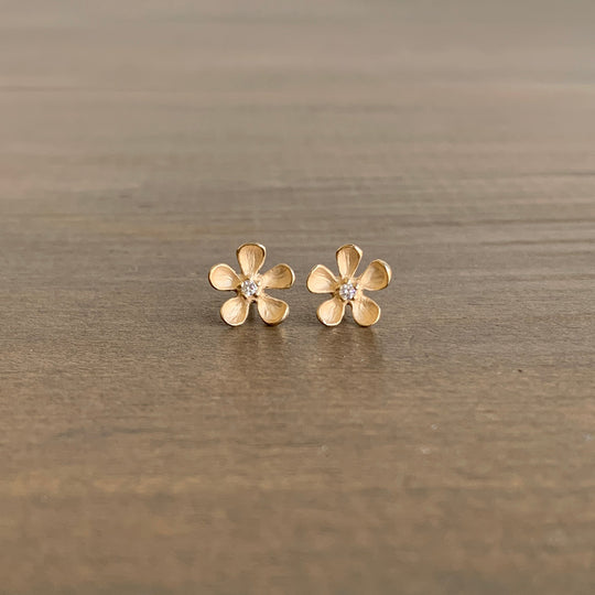 Gold flower-shaped earrings on a wooden surface