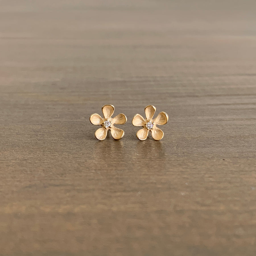 Gold flower-shaped earrings on a wooden surface