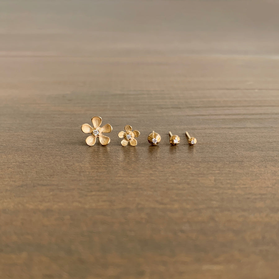 Set of gold flower-shaped earrings on a wooden surface