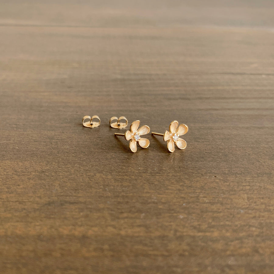 Gold flower-shaped earrings on a wooden surface