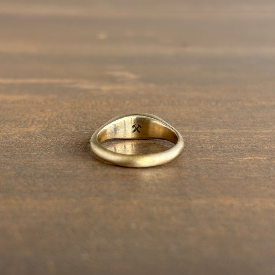 Gold ring with a small design on a wooden surface