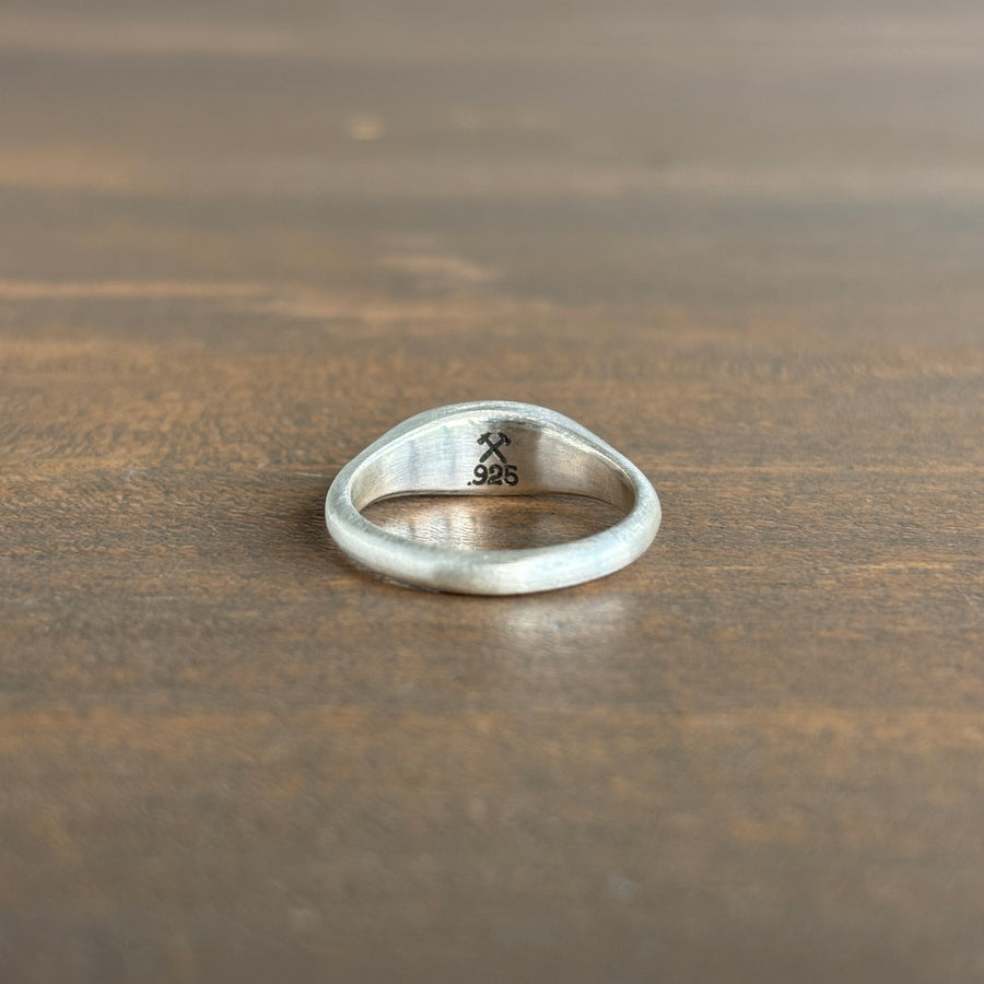 Silver ring with engraved design on a wooden surface