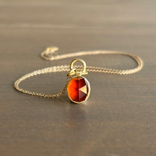 Necklace with a red gemstone pendant on a neutral background