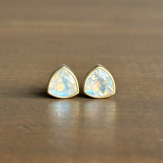 Pair of gold-trimmed teardrop-shaped earrings on a wooden surface