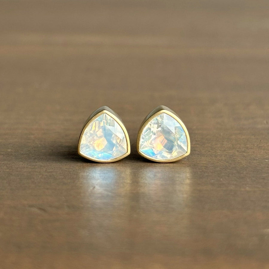 Pair of gold-trimmed teardrop-shaped earrings on a wooden surface
