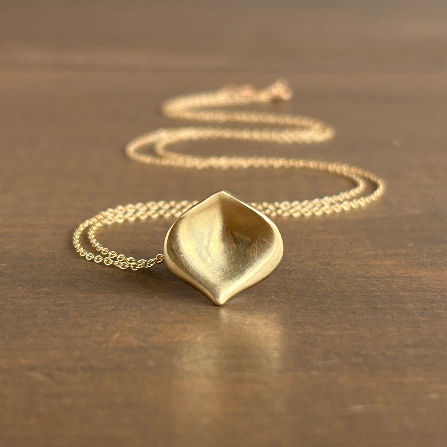 Gold necklace with a unique pendant on a brown surface
