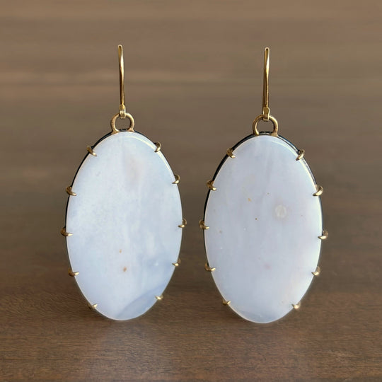 Pair of earrings with light blue stones on a brown background