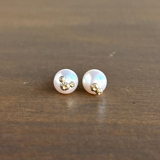 Pair of pearl earrings with gold accents on a wooden surface