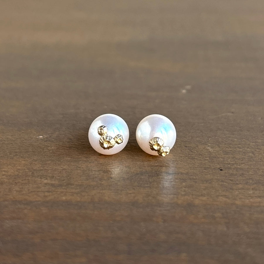Pair of pearl earrings with gold accents on a wooden surface