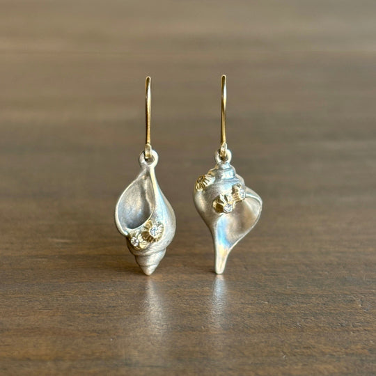 Pair of silver shell-shaped earrings on a wooden surface