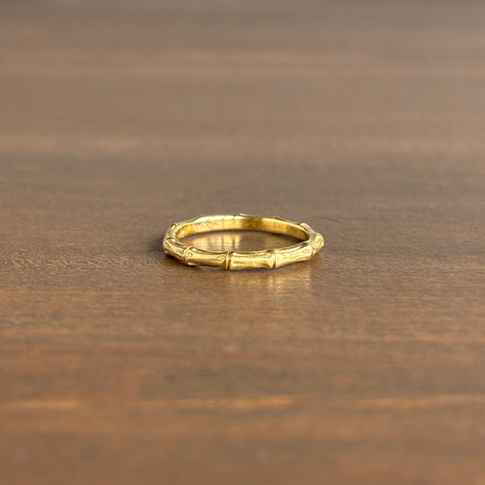 Gold ring with bamboo design on a wooden surface