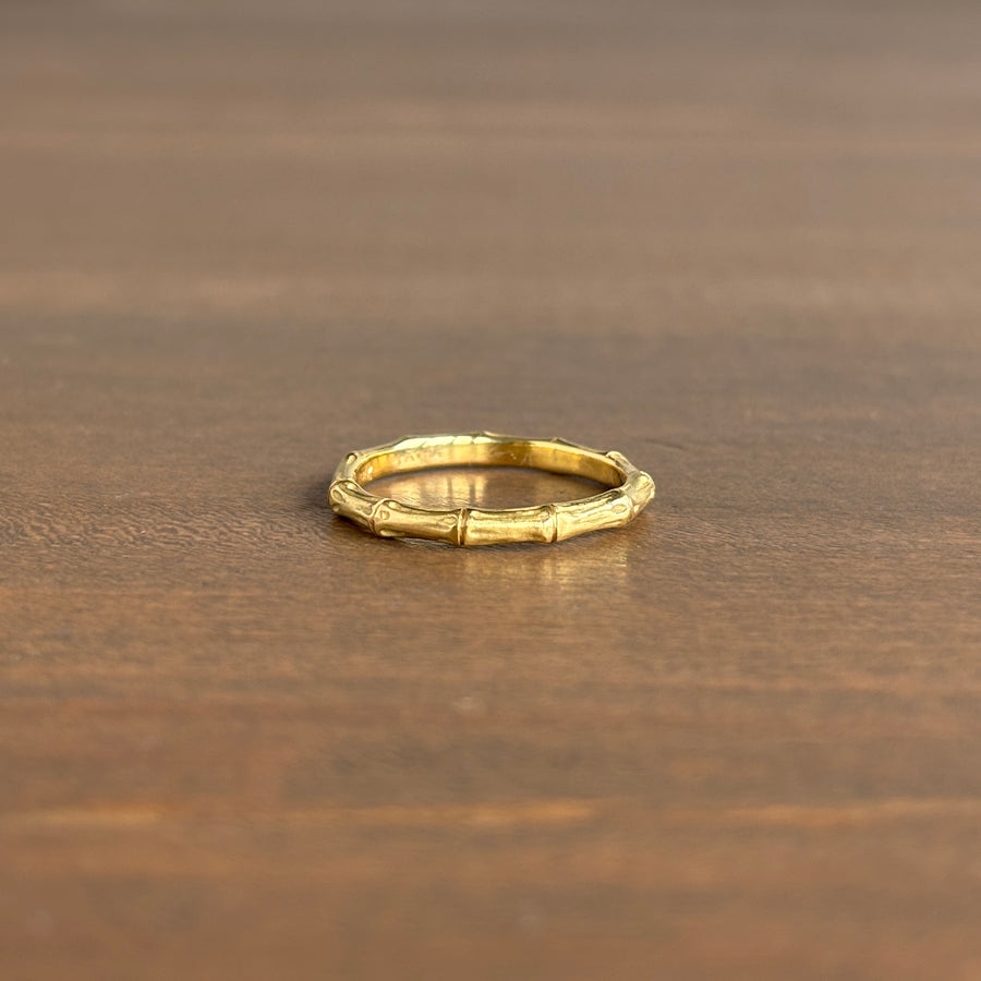 Gold ring with bamboo design on a wooden surface
