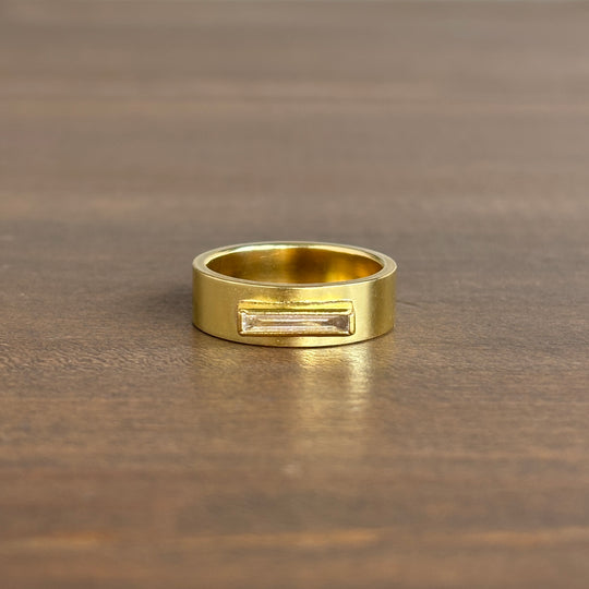 Gold diamond ring with a rectangular engraving on a wooden surface
