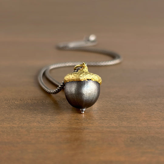 Necklace with a acorn pendant on a wooden surface