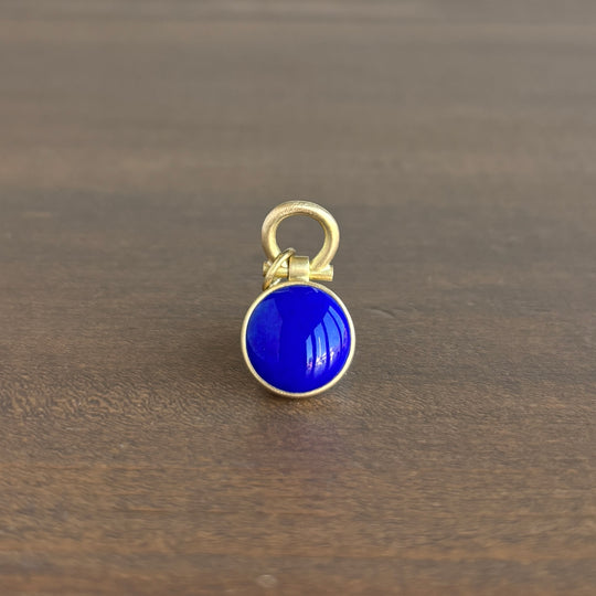 Gold pendant with a blue stone on a wooden surface