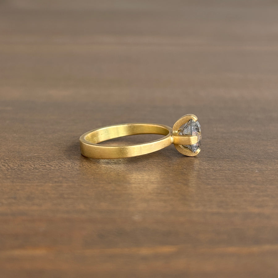 Gold ring with a heart-shaped gemstone on a wooden surface