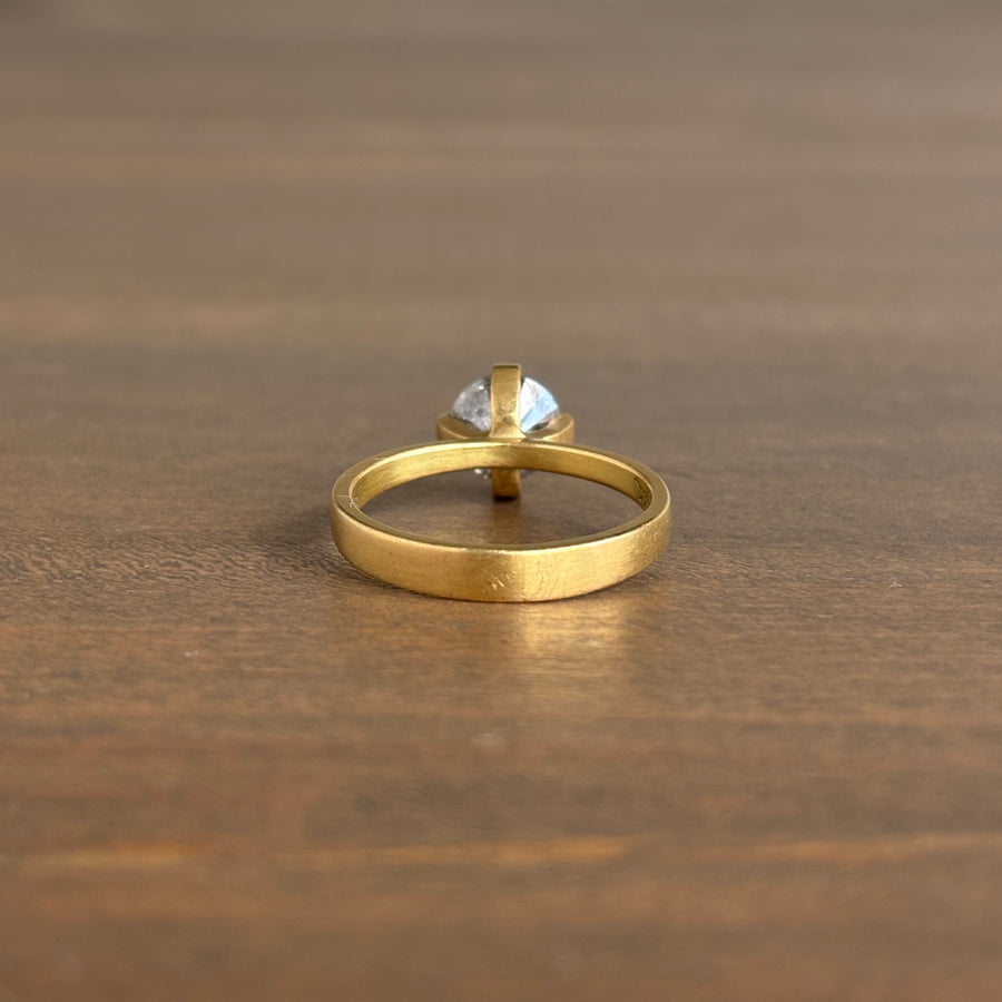 Gold ring with a clear gemstone on a wooden surface