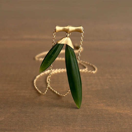 Gold necklace with green leaves on a brown background