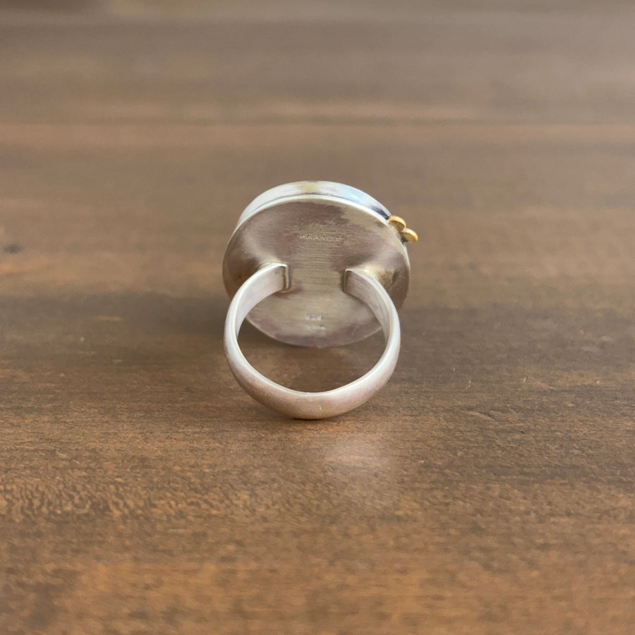 Silver ring with a textured band on a wooden surface