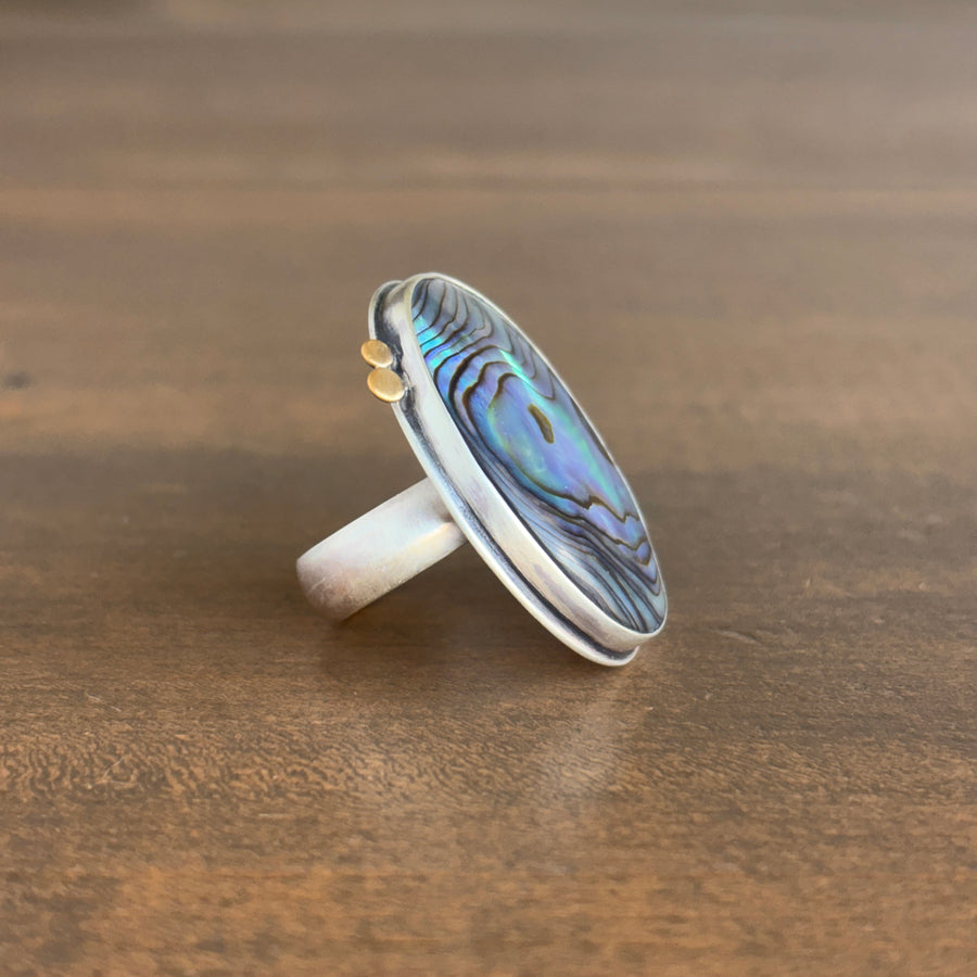 Silver ring with a colorful stone on a wooden surface