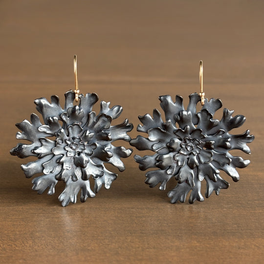 Pair of silver floral earrings on a wooden surface