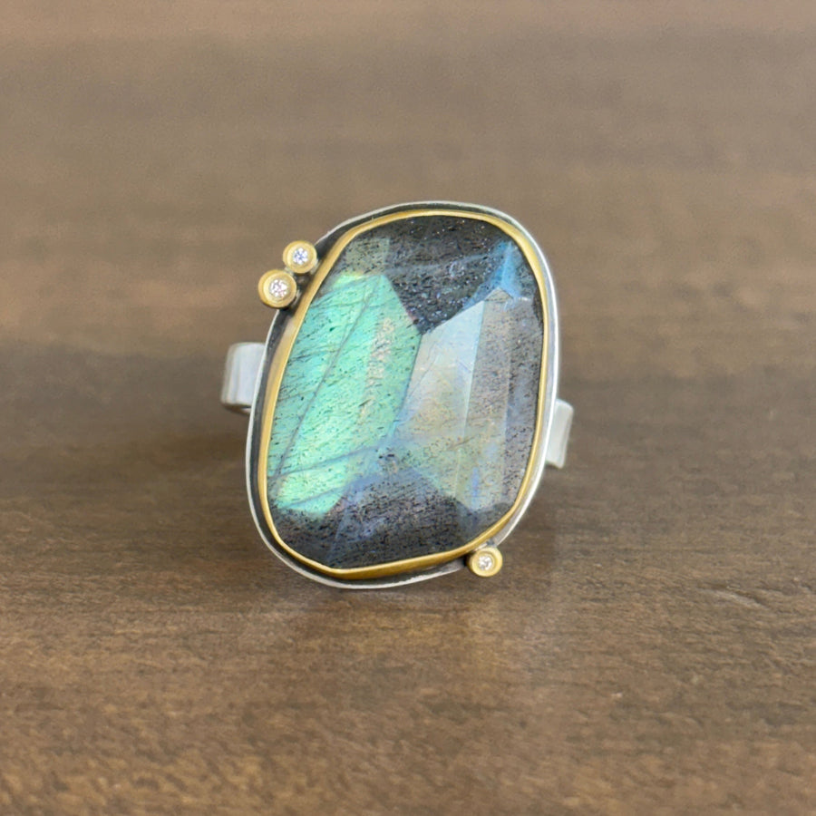 Ring with a labradorite stone and tiny diamonds on a wooden surface