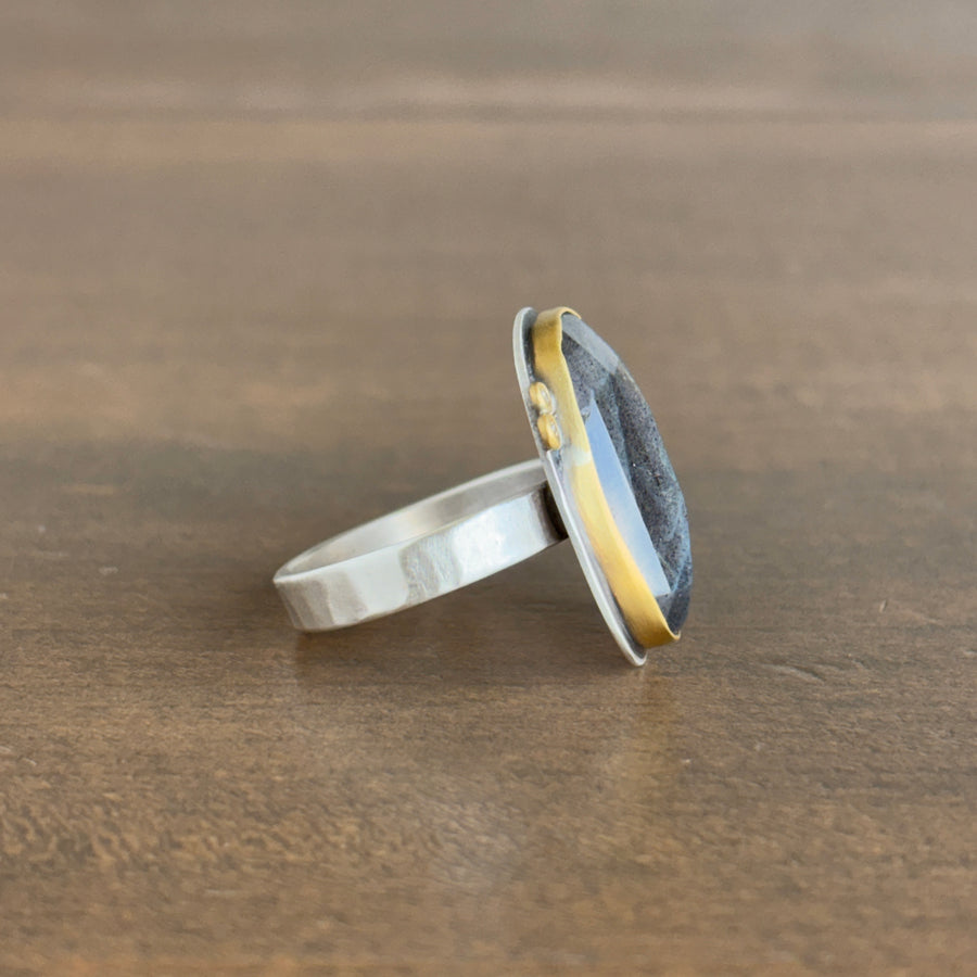 Silver ring with a gold accent on a wooden surface