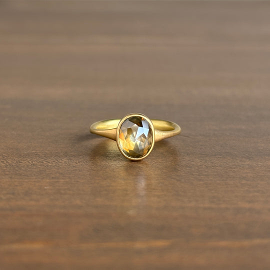 Gold ring with a faceted gemstone on a wooden surface