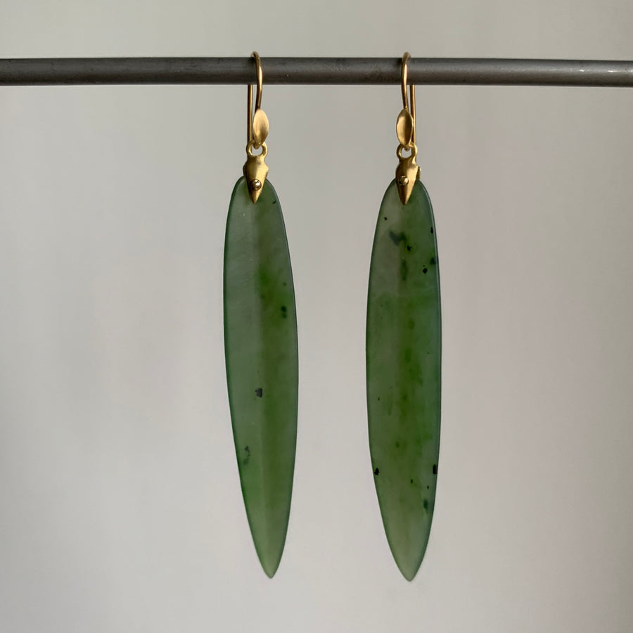 Green jade earrings with gold hooks on a gray background
