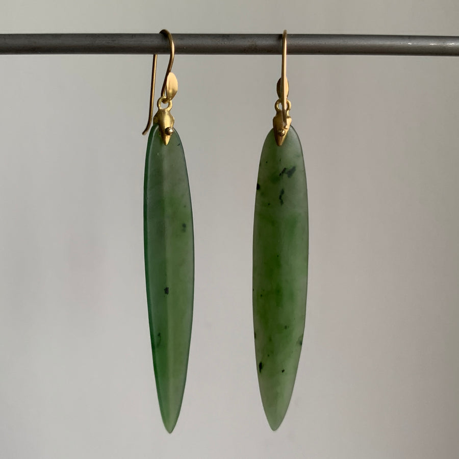 Green jade earrings with gold hooks on a gray background