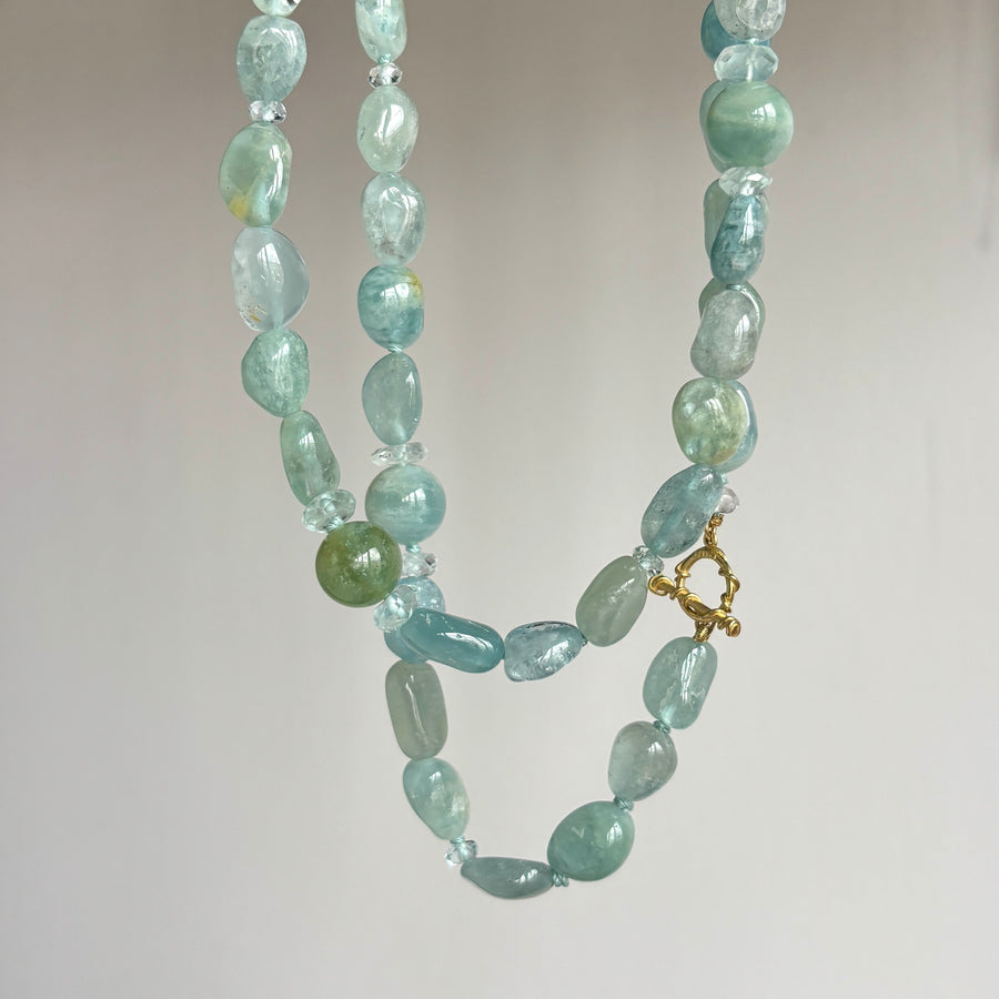 A beaded necklace made of light blue and green translucent stone beads with a small gold clasp, photographed against a plain light background.