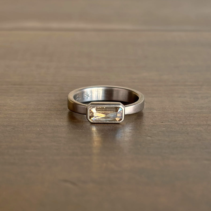 Silver ring with a rectangular gemstone on a wooden surface