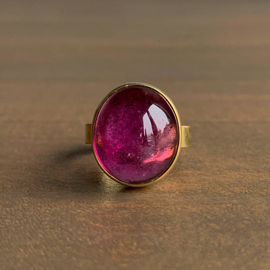 Gold ring with a pink gemstone on a brown surface