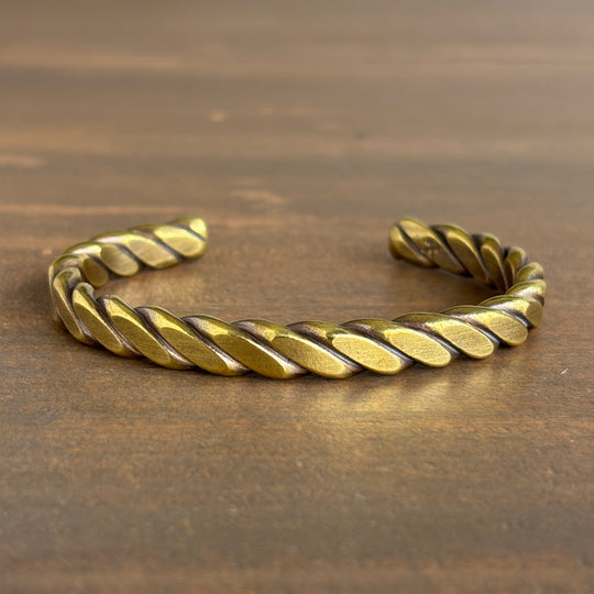 Gold braided bracelet on a wooden surface