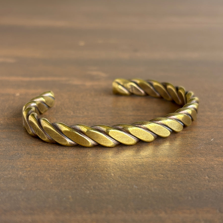 Gold braided bracelet on a wooden surface