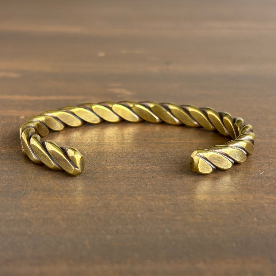Gold braided bracelet on a wooden surface